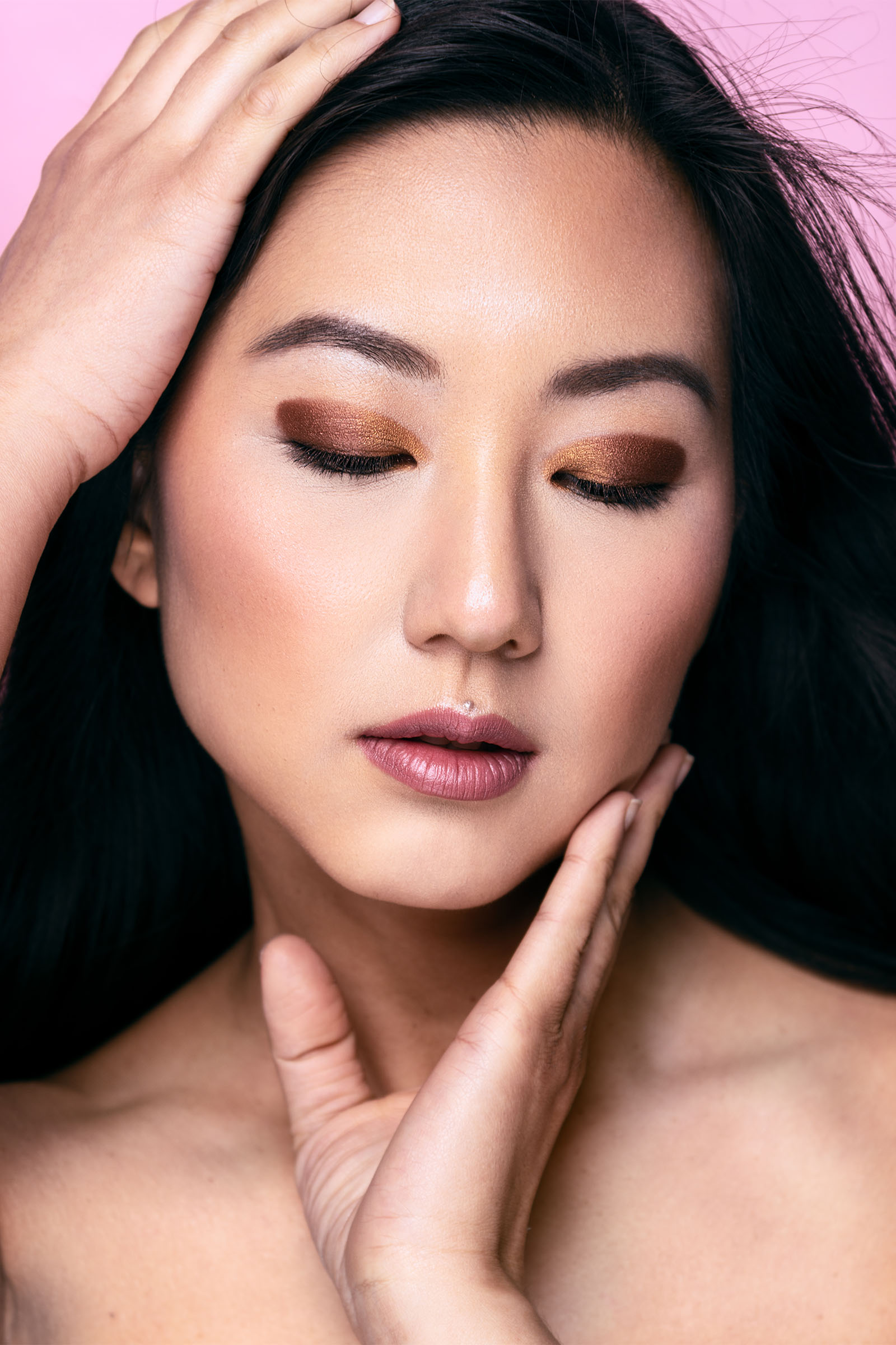 Asian female model closeup beauty portrait featuring gold and clean makeup, hands on her face and head, long hair by Utah photographer Christopher Loke