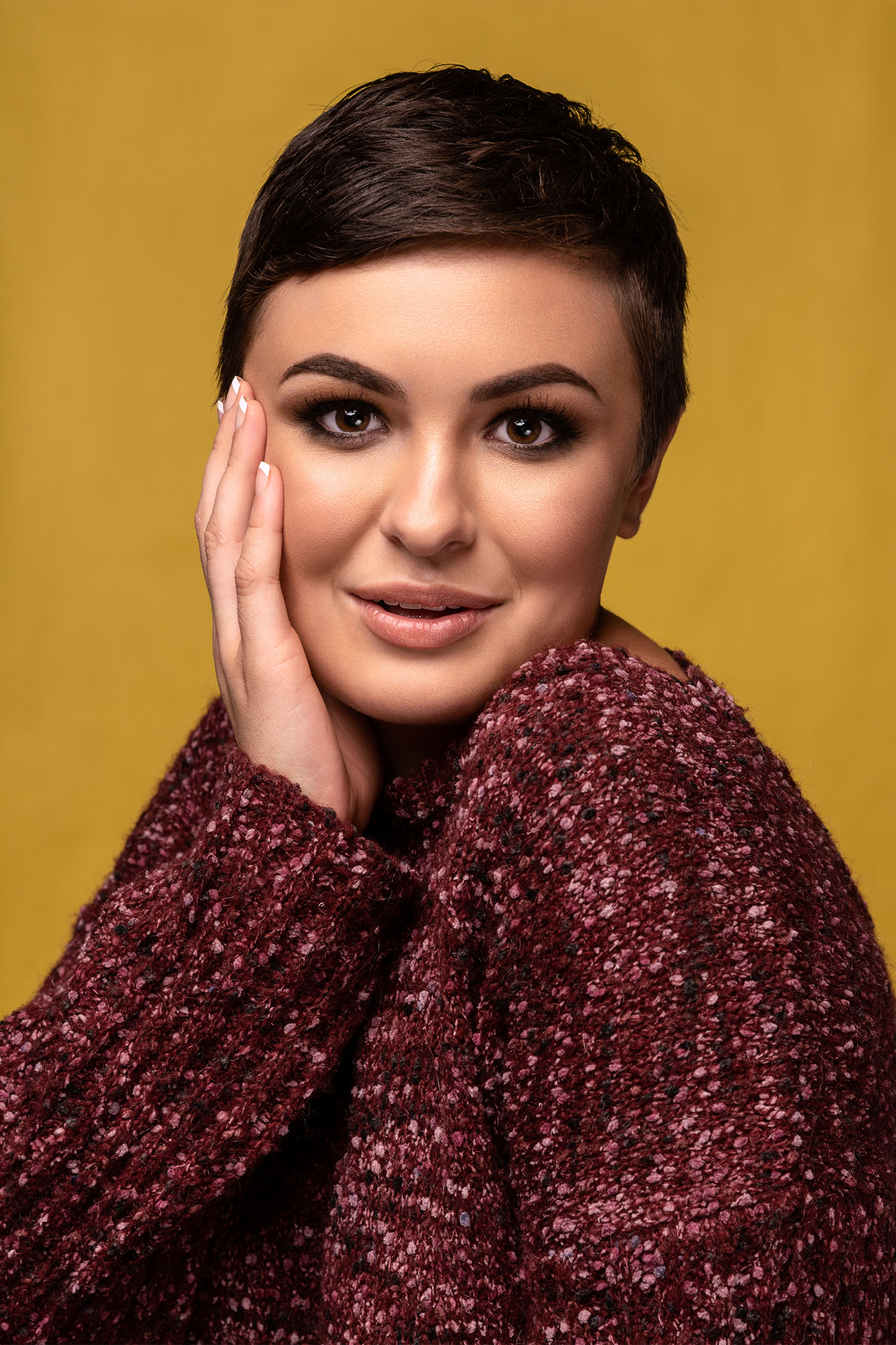 Beauty portrait of a female model, mustard background, hand on her face, pixie haircut by Utah photographer Christopher Loke